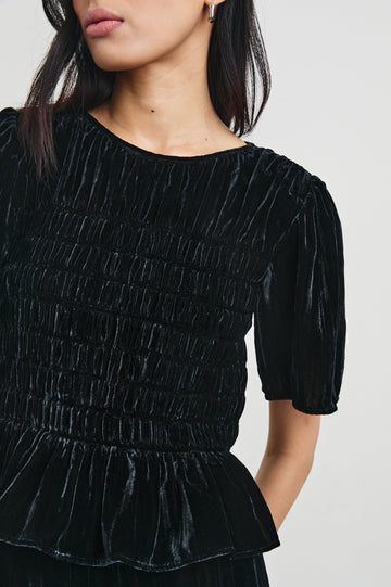 Rosie Short-Sleeve Top with a Smocked Center Bodice, Pleats at the Hem and Yoke and a Upper Back Button Closure in Black Velvet Colorway - Front View Featured on Model