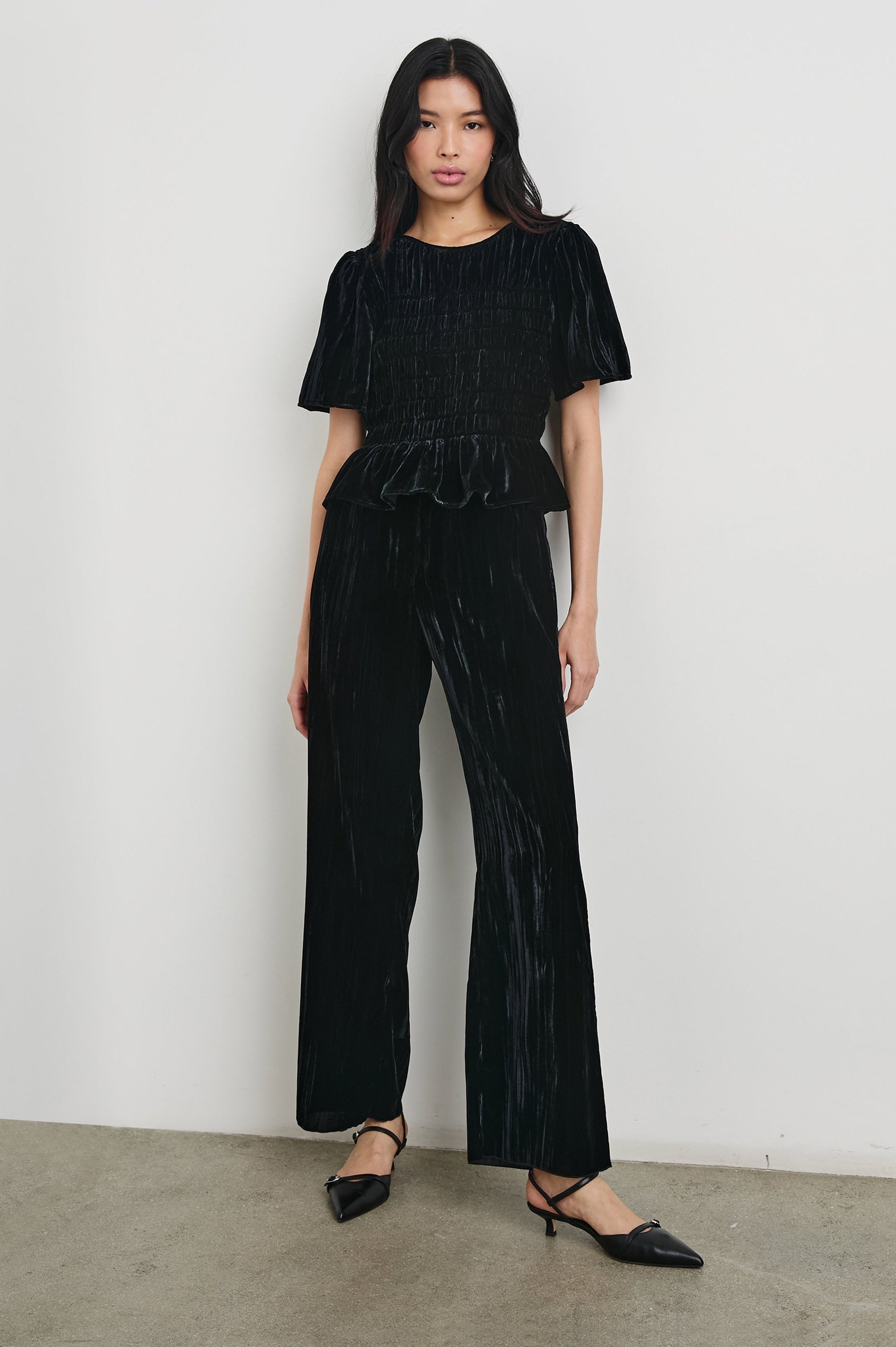 Rosie Short-Sleeve Top with a Smocked Center Bodice, Pleats at the Hem and Yoke and a Upper Back Button Closure in Black Velvet Colorway - Front View Full Body Featured on Model