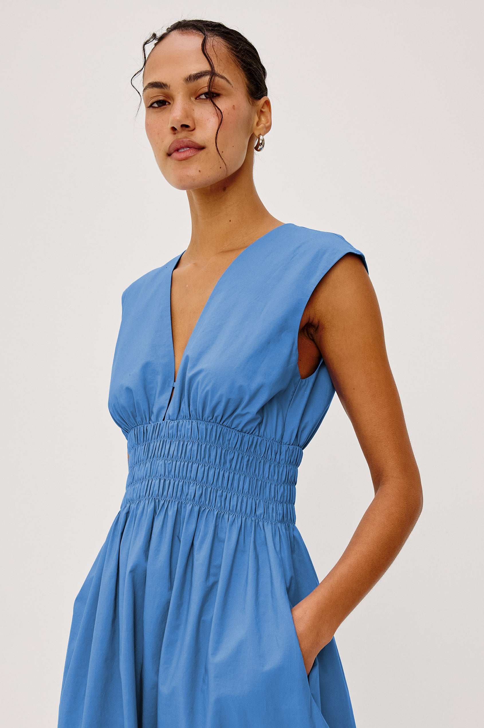 Roxanne Midi Dress in Cotton Poplin With Shirred Shoulders, Plunging V-Neck, Smocked Waist and Seashell Hem Embroidery in Harbor Blue Colorway - Upper Body Front View Featured on Model