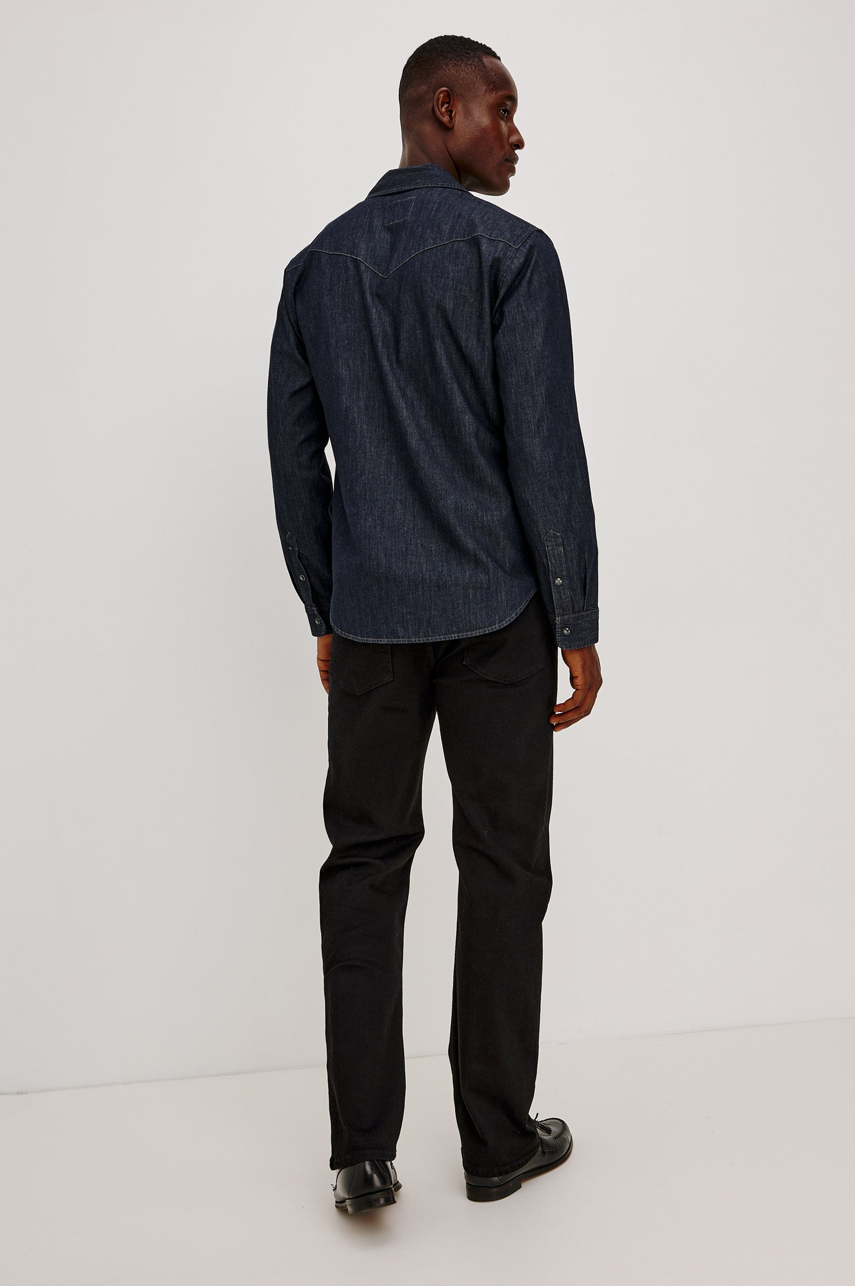 Roy Shirt in Rigid Rinsed Denim With Western Shoulder and Back Yokes, Spread Collar, Snap Front, Dual Chest Flap Pockets, and Shirttail Hem in Twilight Wash Colorway - Full Body Back View Featured on Model