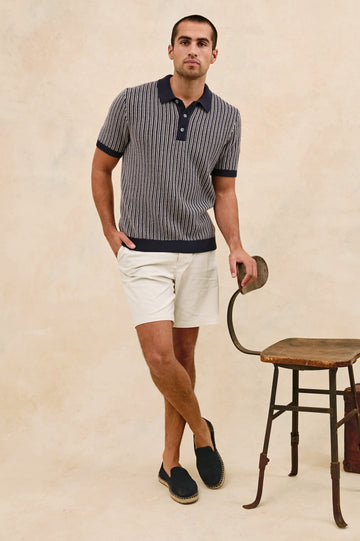 Royce ribbed knit short sleeve polo with three front buttons and a collar in Navy Grey - stylized full body front view on model, with chair