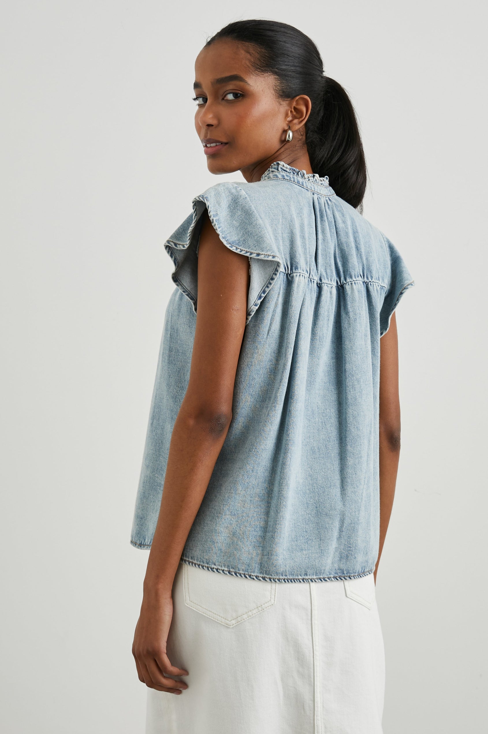 Ruthie Top with Flutter Cap Sleeves, a Ruffled Banded Collar, Buttons Down the Front, and Soft Shirring at Front Yoke in Faded Indigo Colorway - Back  View Featured on Model