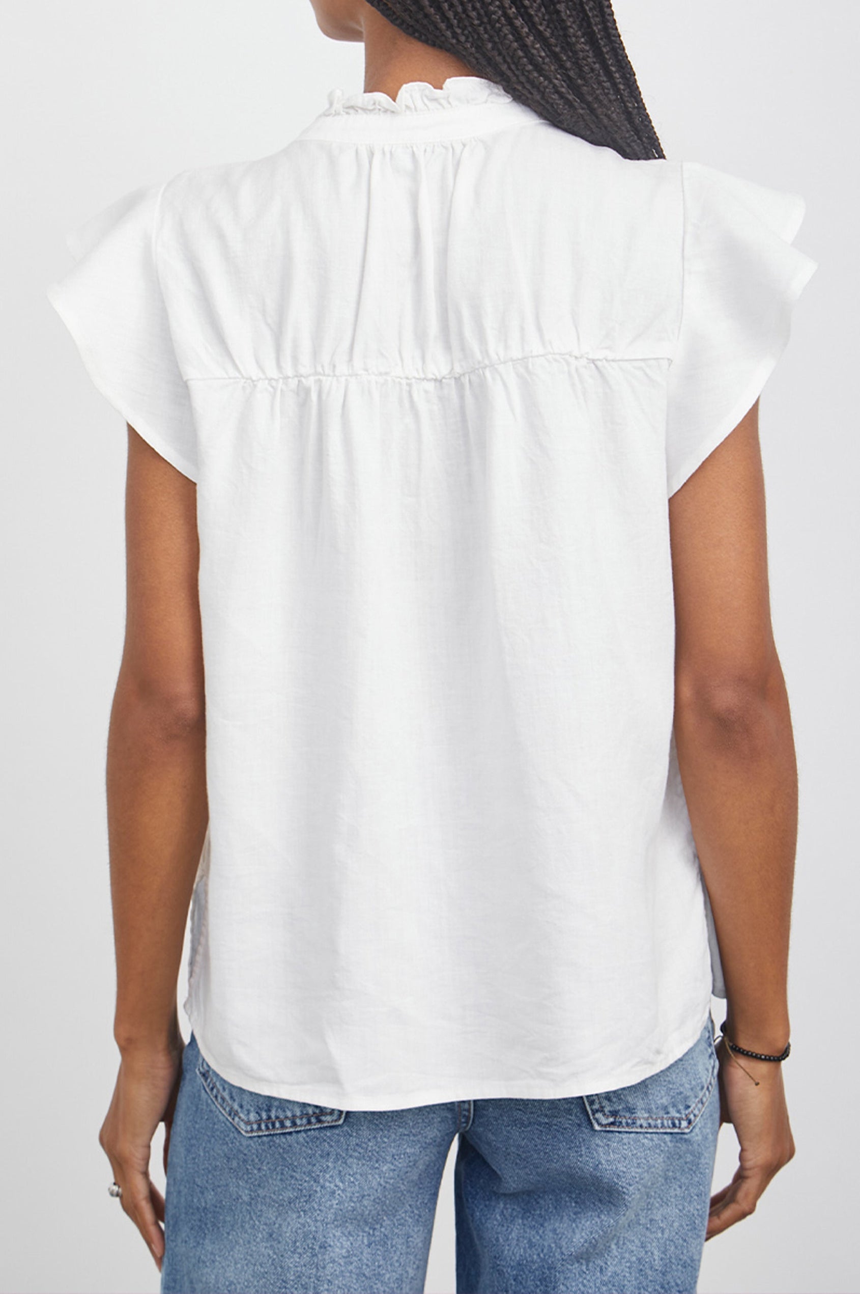 Ruthie Top with Flutter Cap Sleeves, a Ruffled Banded Collar, Buttons Down the Front, and Soft Shirring at Front Yoke in White Colorway - Back View Featured on Model