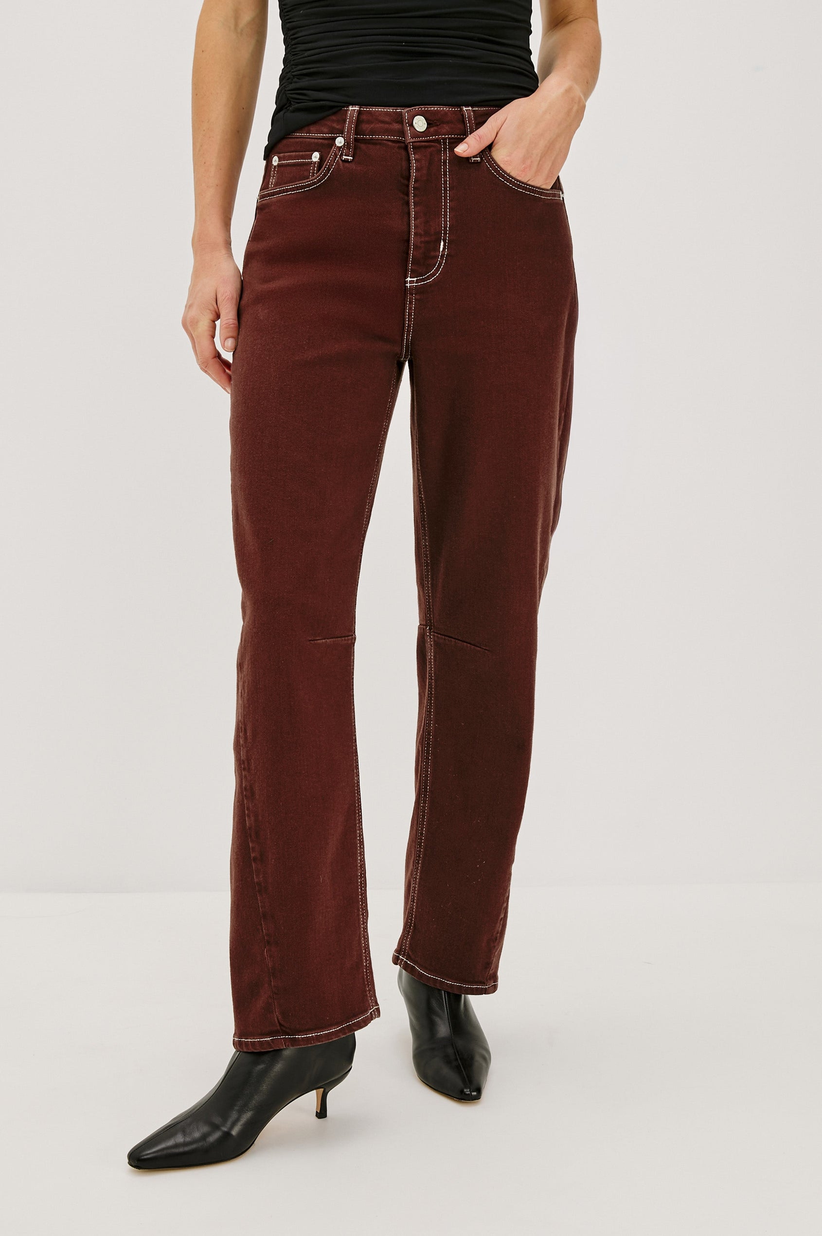 The Samo is a denim barrel leg jean, it features a low-slung fit in light-stretch denim with darting details and a subtle curved seam in Chocolate Contrast Stitch colorway. Front view featured on model.