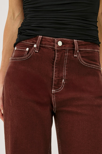 The Samo is a denim barrel leg jean, it features a low-slung fit in light-stretch denim with darting details and a subtle curved seam in Chocolate Contrast Stitch colorway. Front view featured on model.