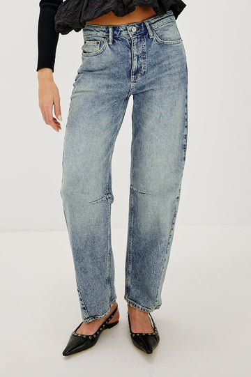 The Samo is a denim barrel leg jean, it features a low-slung fit in light-stretch denim with darting details and a subtle curved seam in Desert Sky wash, a vintage wash with yellow tint. Front view featured on model.