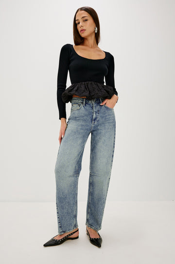 The Samo is a denim barrel leg jean, it features a low-slung fit in light-stretch denim with darting details and a subtle curved seam in Desert Sky wash, a vintage wash with yellow tint. Front full body view featured on model.