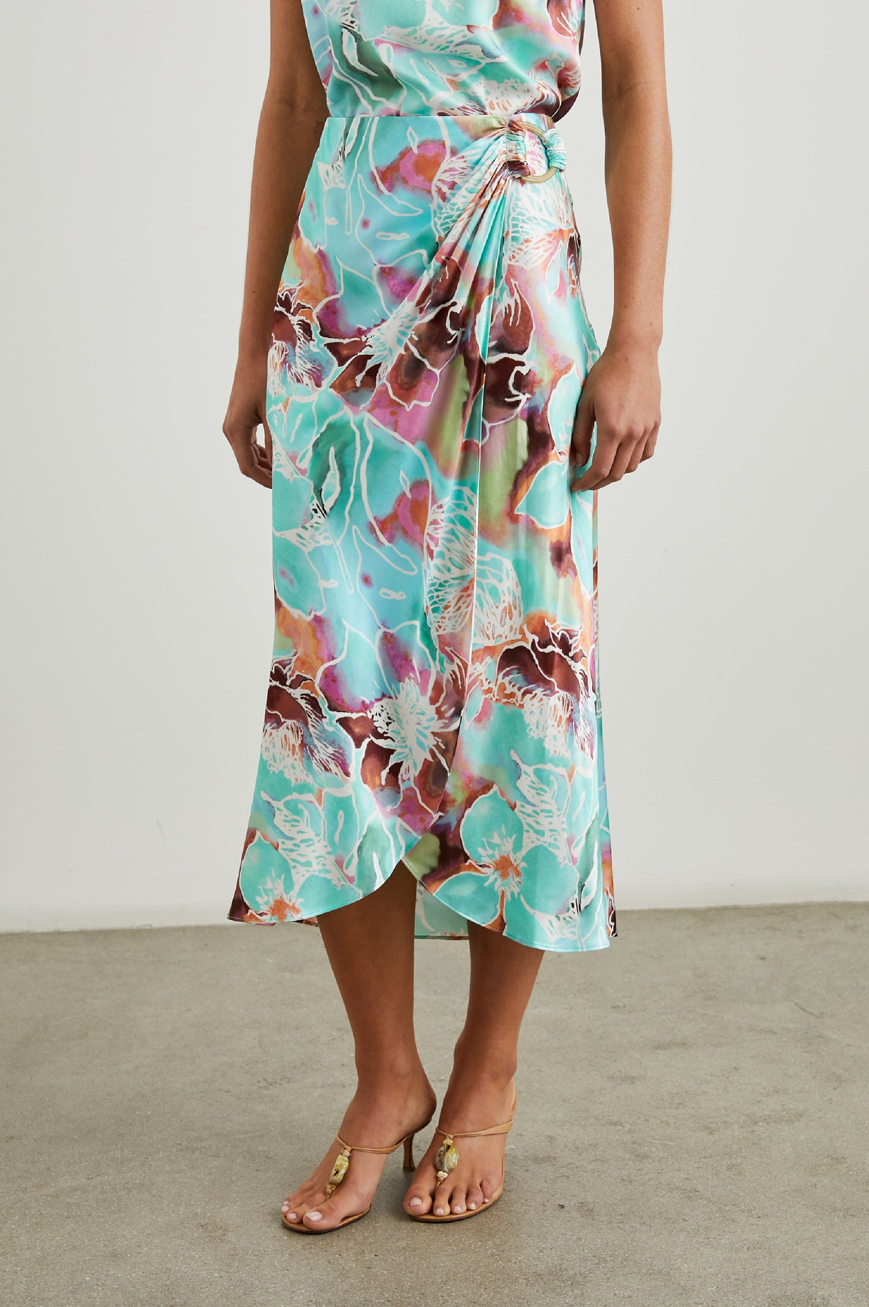 Sampha Faux Wrap Midi Skirt with a D Ring Horn Faux Closure in Kauai Floral Colorway, Flowers in Pinks, Browns, Blues, Greens and White - Front View Featured on Model 