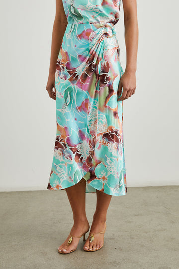 Sampha Faux Wrap Midi Skirt with a D Ring Horn Faux Closure in Kauai Floral Colorway, Flowers in Pinks, Browns, Blues, Greens and White - Front View Featured on Model 