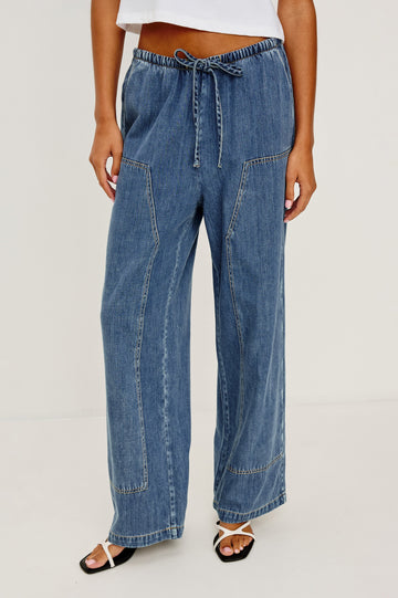 The Sanderson is a wide leg pull on pant with an encased drawstring waist tie, it has workwear inspired contrast topstitching on the front leg panels. Front view featured on model.