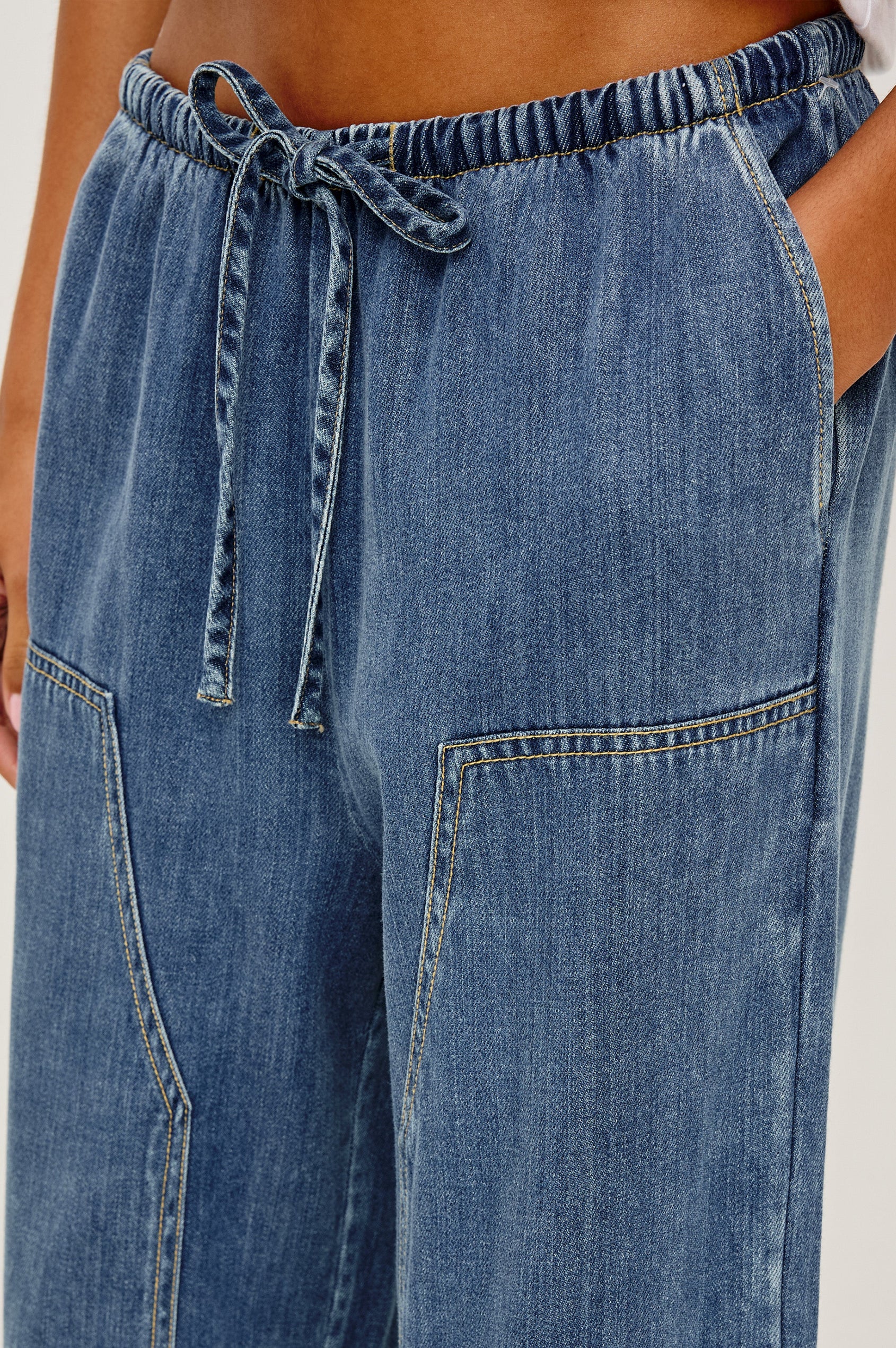 The Sanderson is a wide leg pull on pant with an encased drawstring waist tie, it has workwear inspired contrast topstitching on the front leg panels. Close Up of Details featured on model.