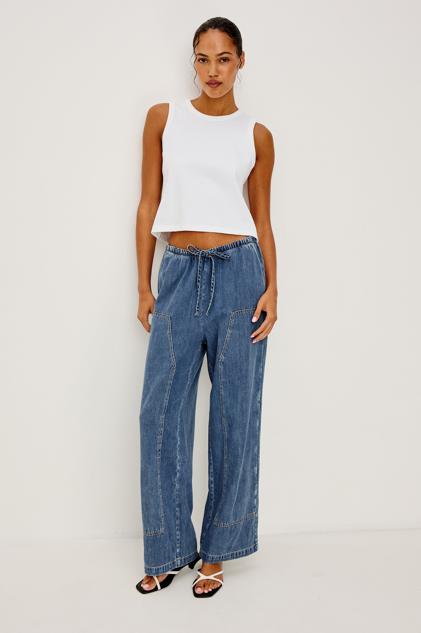 The Sanderson is a wide leg pull on pant with an encased drawstring waist tie, it has workwear inspired contrast topstitching on the front leg panels. Full body front view featured on model.