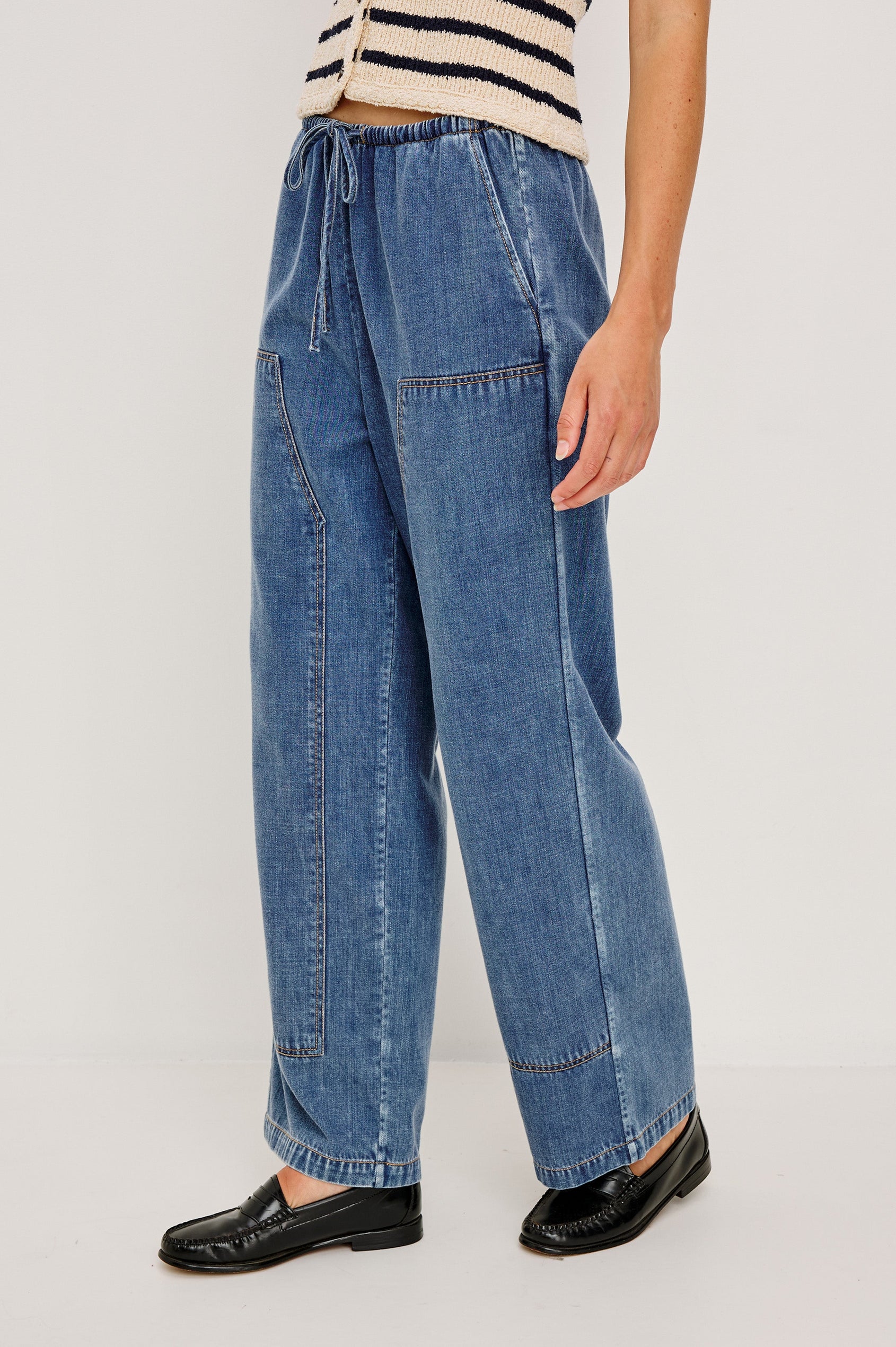 The Sanderson is a wide leg pull on pant with an encased drawstring waist tie, it has workwear inspired contrast topstitching on the front leg panels. Side view featured on model.