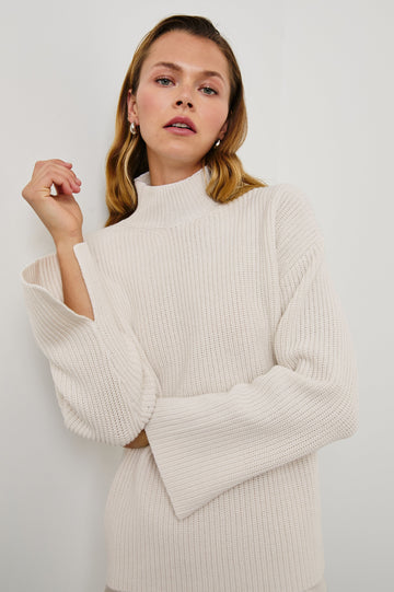 Sanna Long Sleeve Knit Sweater with a Funnel Neck and Slits at the Back of the Neck and on the Cuffs in Hazy Dust Colorway - Front View Featured on Model