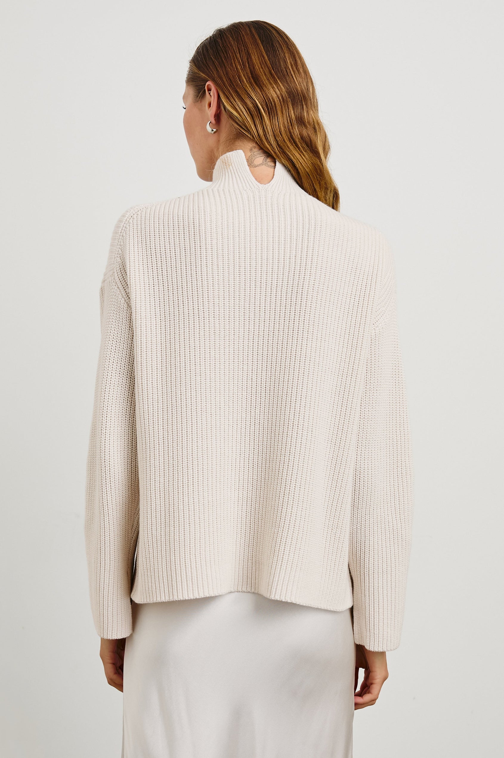 Sanna Long Sleeve Knit Sweater with a Funnel Neck and Slits at the Back of the Neck and on the Cuffs in Hazy Dust Colorway - Back View Featured on Model
