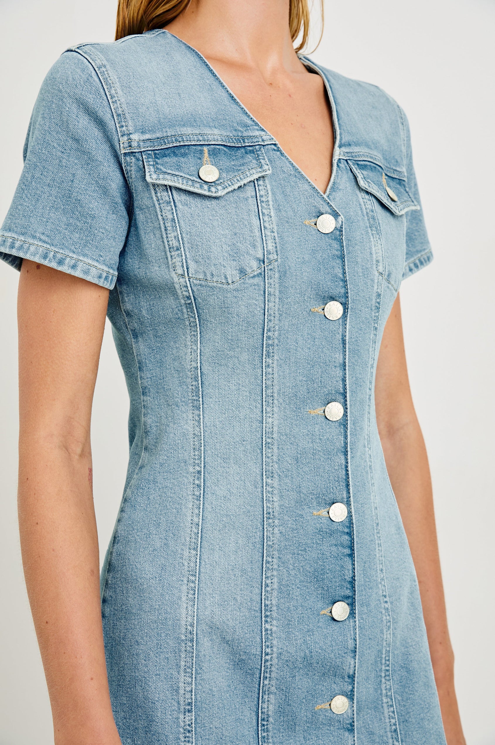 Saratoga a-line mini button down denim dress with two front chest pockets. Short sleeve and form fitting in Faded Seaglass - close up of details on model