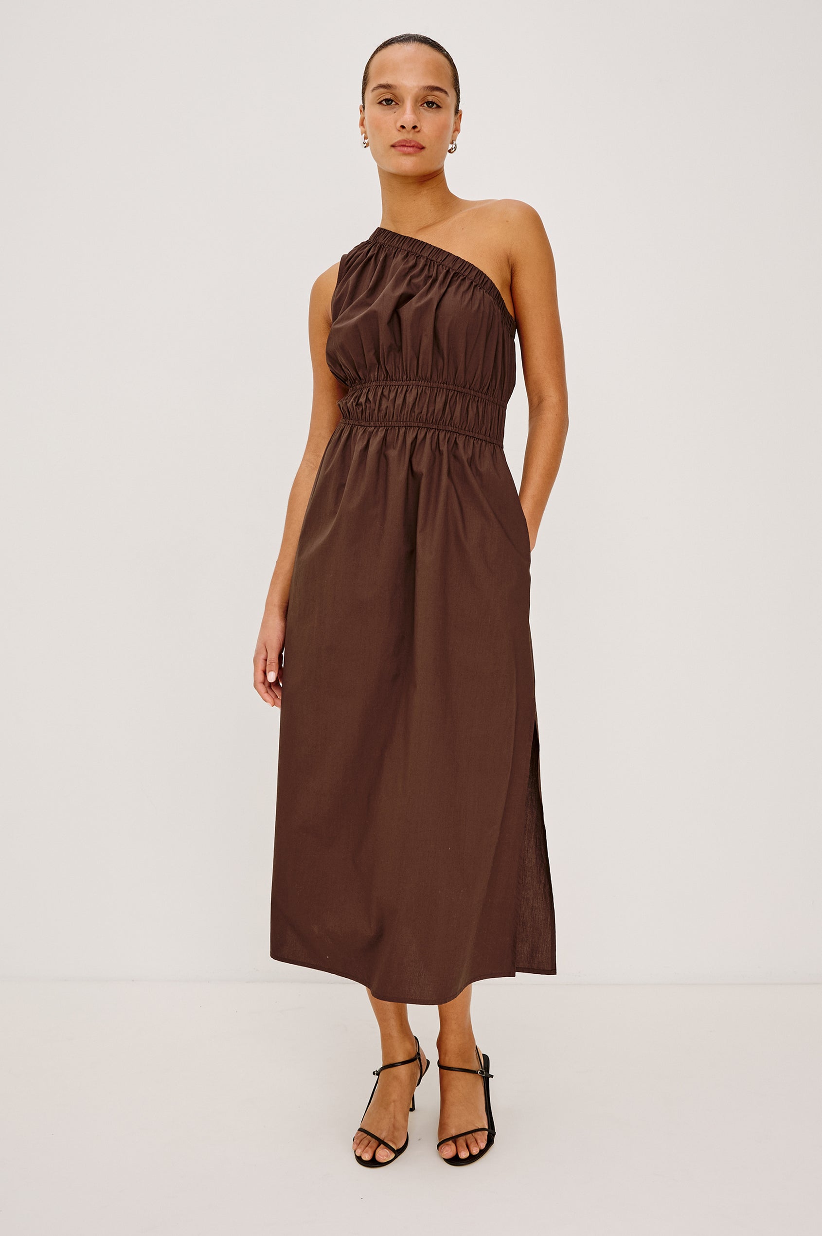 Selani Midi Dress in Cotton Poplin With One-Shoulder Neckline, Shirred Waistband, Concealed Side Pockets, and Side Slit in Espresso Colorway - Full Body Front View Featured on Model
