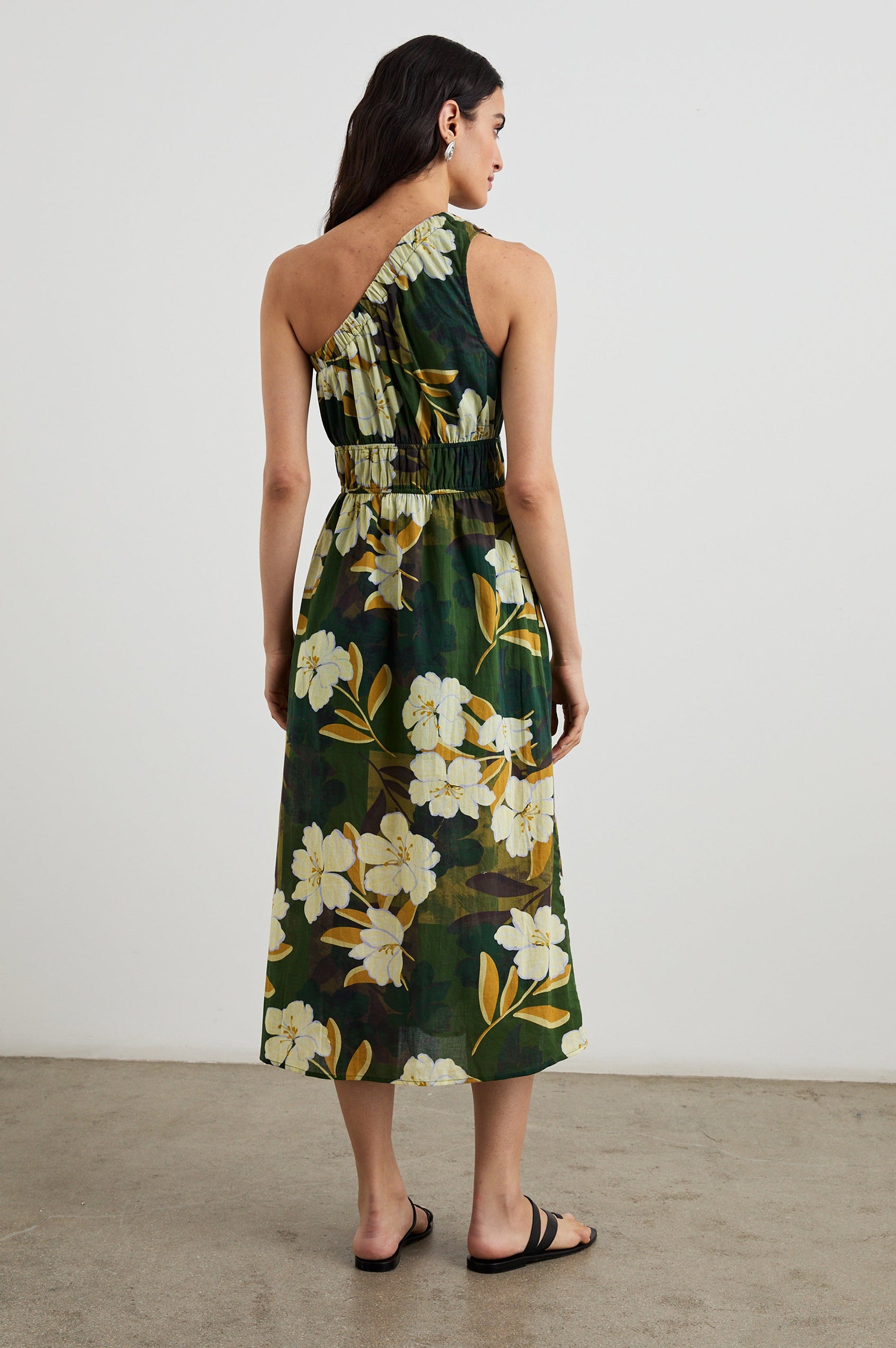 Selani Midi Dress With an Asymmetrical Neckline, Mid-Thigh Slide Slit and Cinched Waistband in Plumerias Colorway, with Ivory and Gold Plumerias on Dark Green  - Back Full Body View Featured on Model