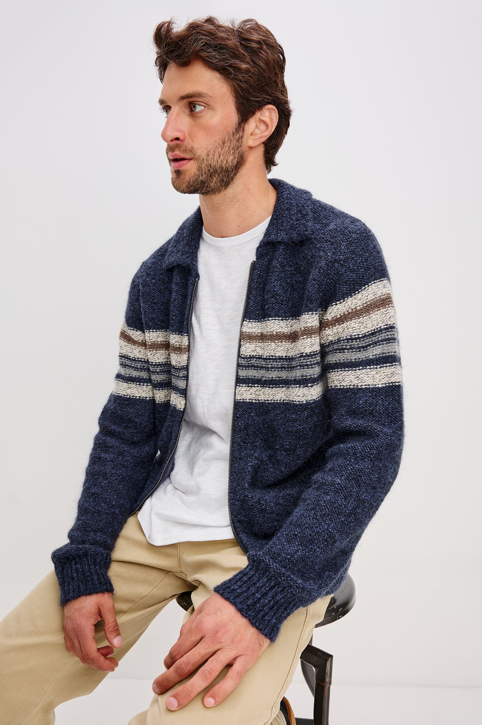 Seldon is a zip front collard sweater jacket with a multi color horizontal stripe design across chest in Moon Shadow colorway. Side seated view featured on model.