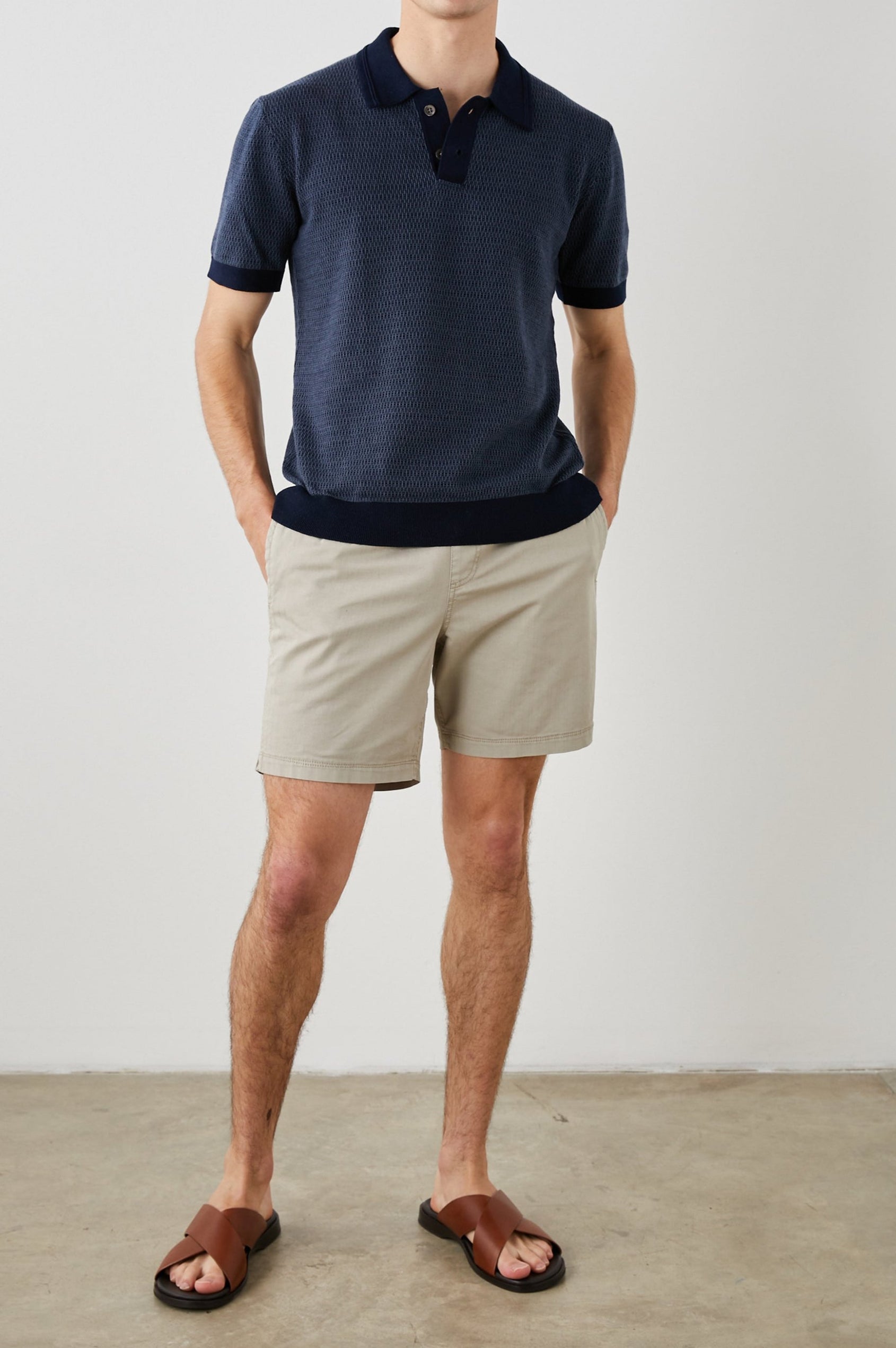 SHOREDITCH NAVY BROQUADE POLO SHIRT - FRONT FULL BODY WITH HANDS IN POCKETS