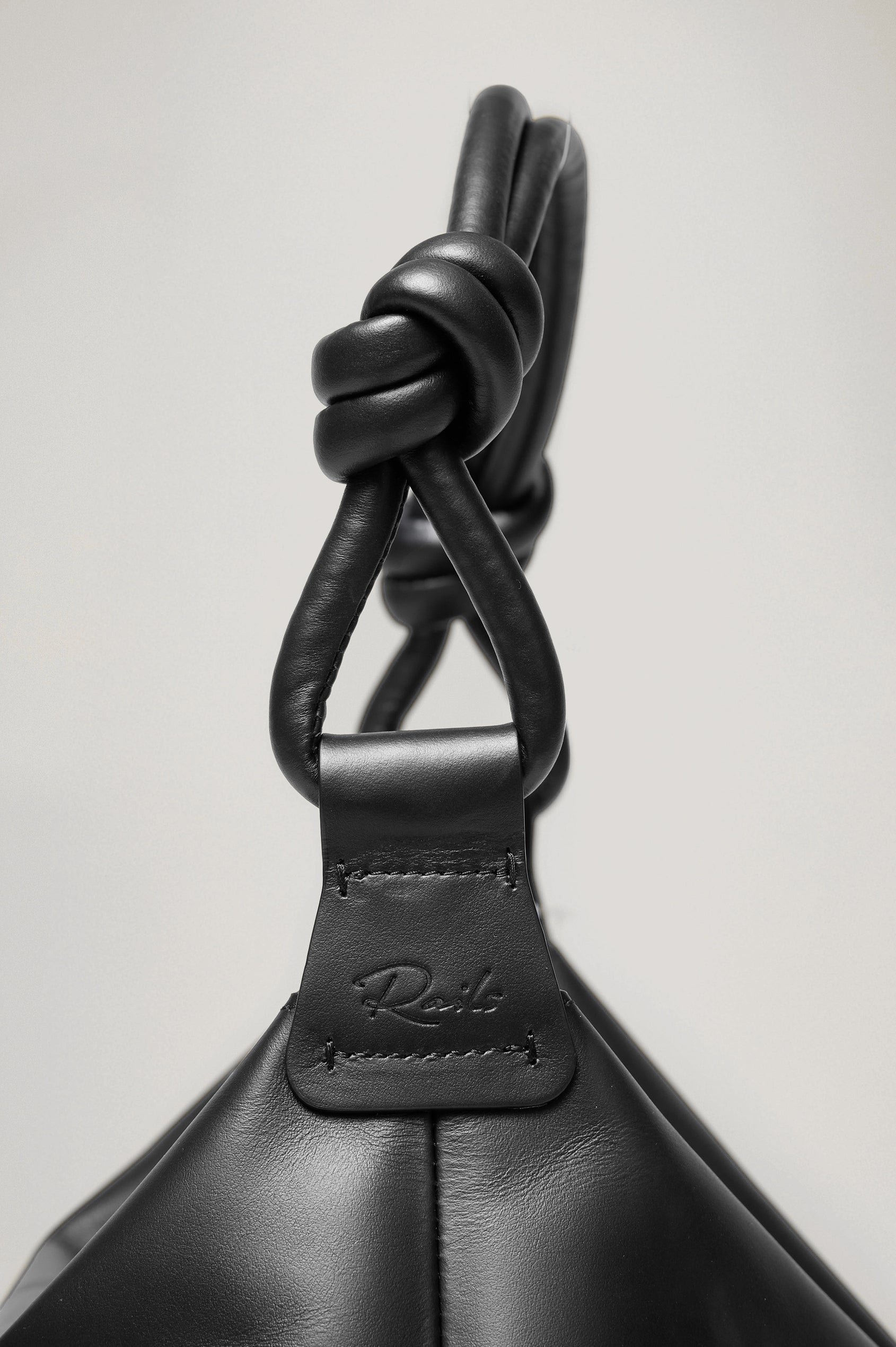 The Siena is a true slouchy hobo bag, crafted from smooth leather with a knotted top strap and a zip closure finished with a fringed tassel. In Black Leather Colorway. Detailed view of strap featured.