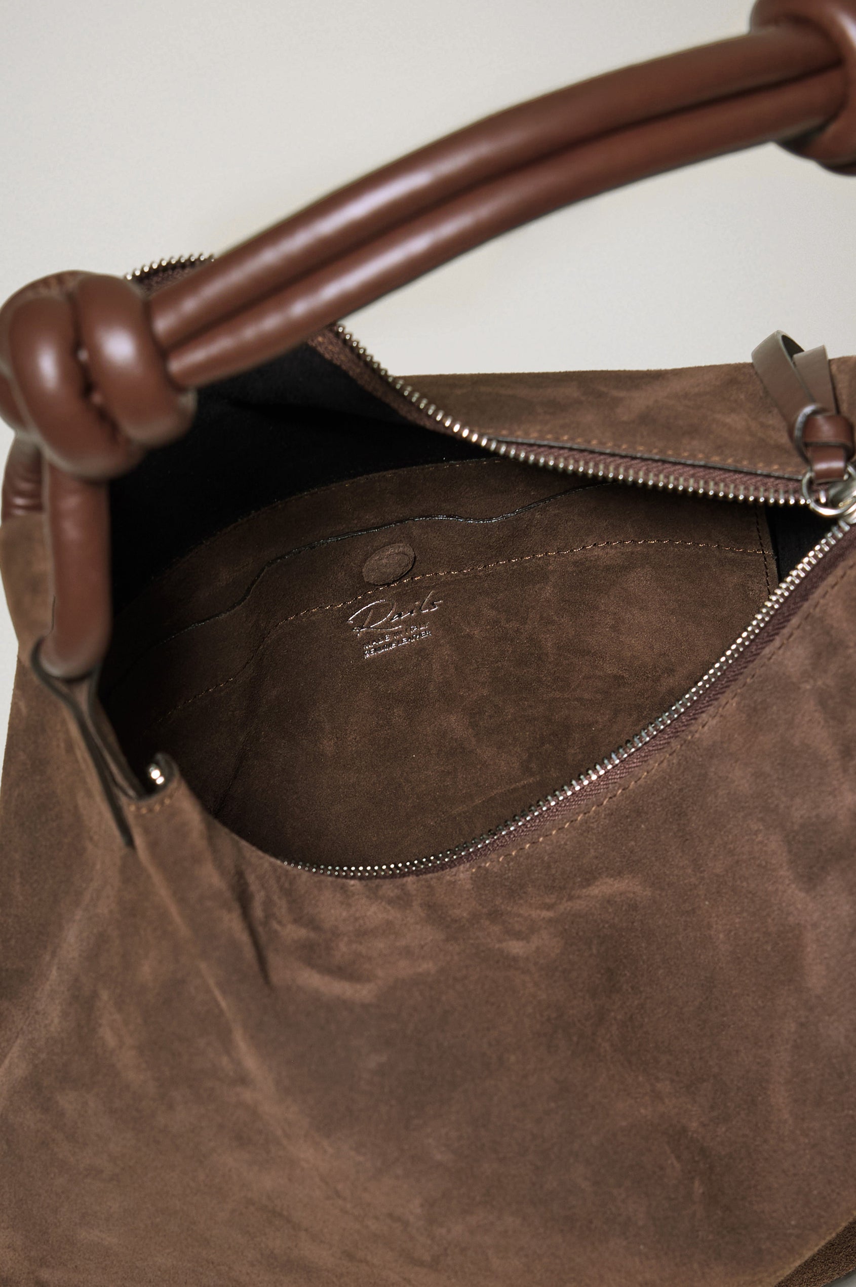 The Siena is a true slouchy hobo bag, crafted from smooth leather with a knotted top strap and a zip closure finished with a fringed tassel. In Espresso Suede Colorway. Detailed view of interior featured.
