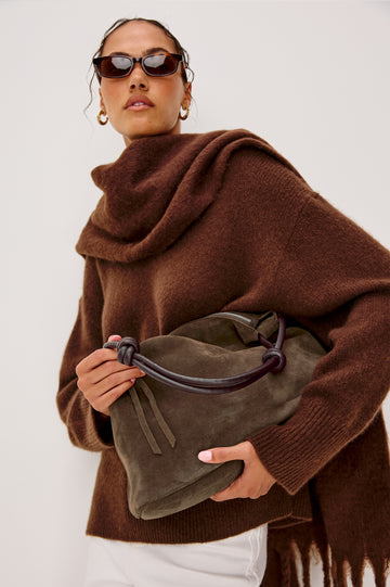 The Siena is a true slouchy hobo bag, crafted from smooth leather with a knotted top strap and a zip closure finished with a fringed tassel. In Espresso Suede Colorway. Front view featured on model.