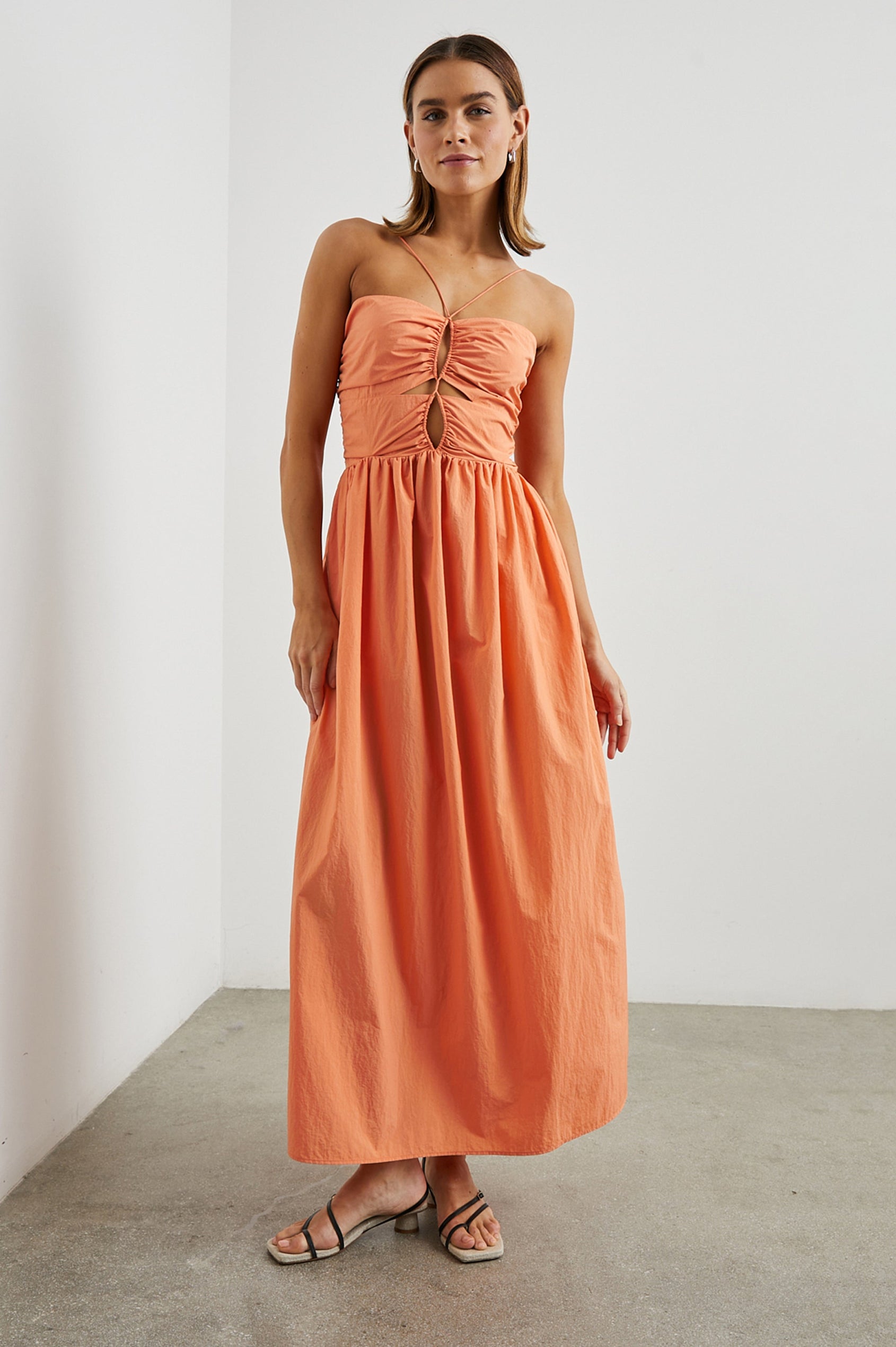 Silvia Sleeveless Maxi Dress with Spaghetti Straps with a Lower Back Tie, an Open Back, and Cutouts Along the Center of the Bodice in Papaya Colorway - Front Full Body  View Featured on Model