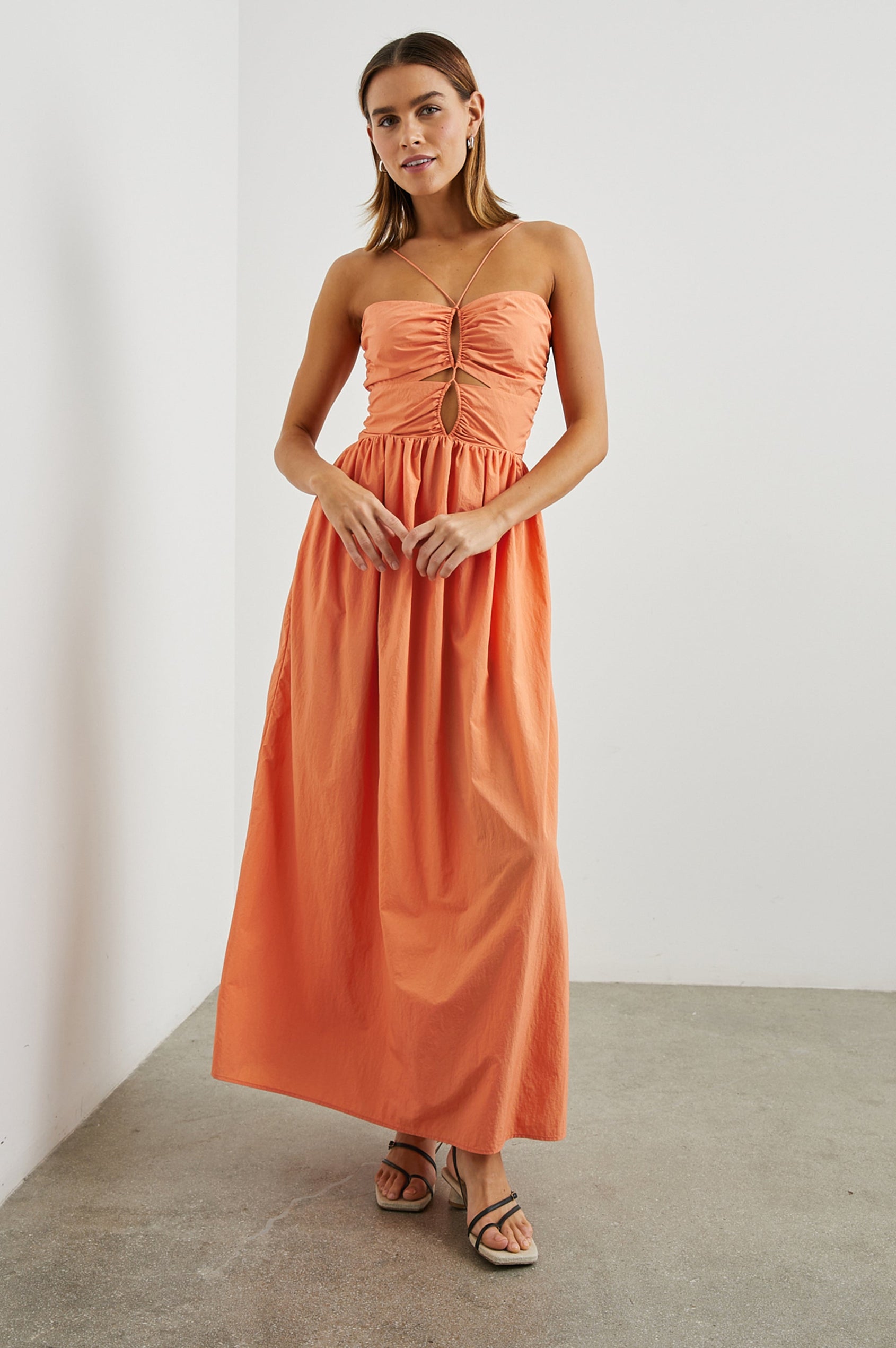 Silvia Sleeveless Maxi Dress with Spaghetti Straps with a Lower Back Tie, an Open Back, and Cutouts Along the Center of the Bodice in Papaya Colorway - Front Full Body  View Featured on Model