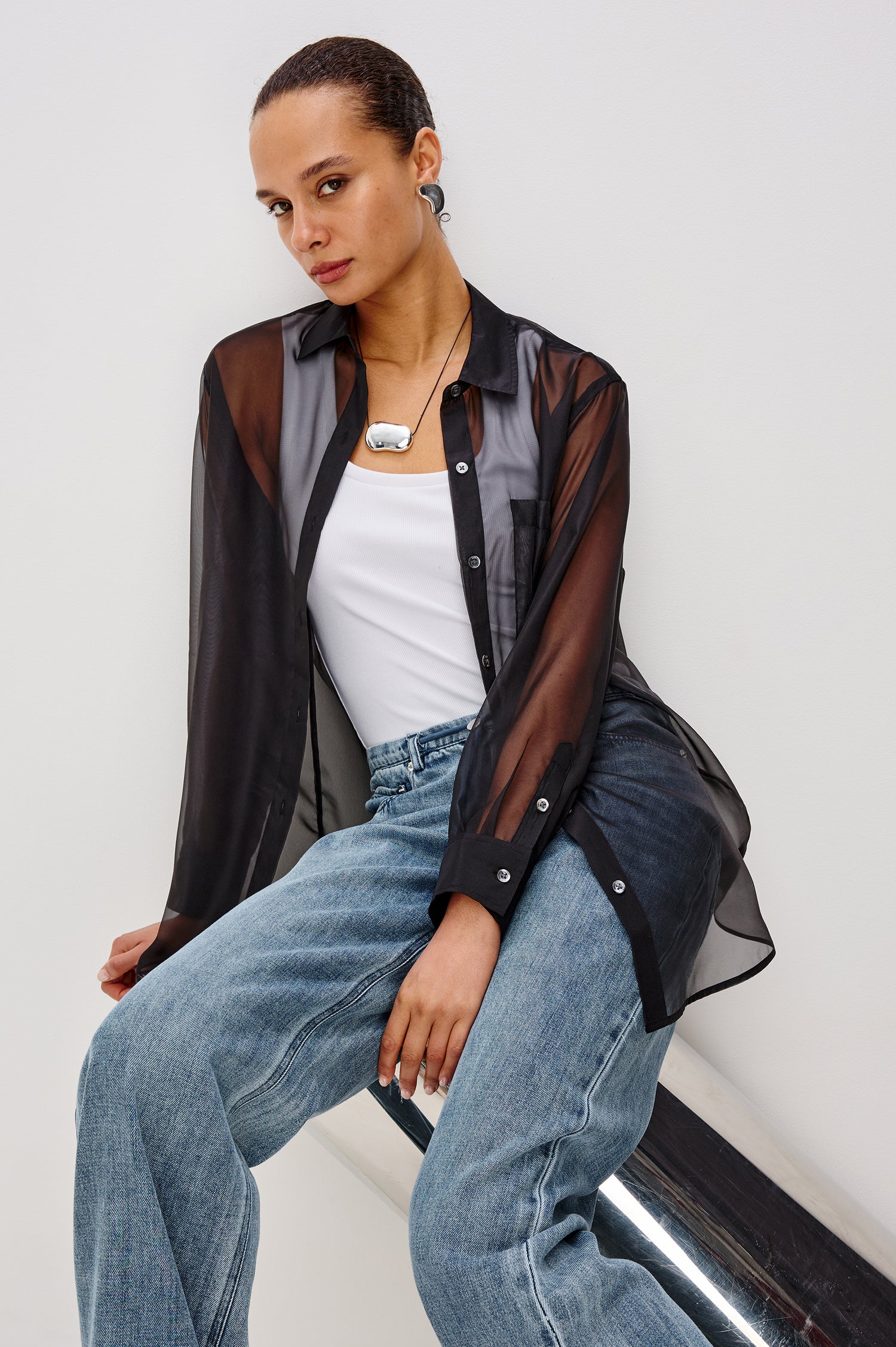 Sofiya Button-Up Shirt in Sheer Organza With Collar and Long Sleeves in Black Colorway - Upper Body Front View Featured on Model Sitting