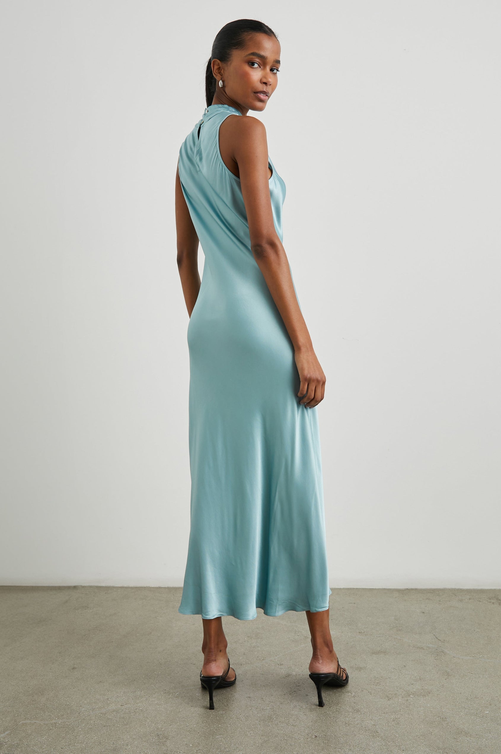 Solana Sleeveless Midi Dress with a High Cowl Collar, Side Slit, and Two Button Keyhole Closure at the Back in Clearwater Colorway, a Blue - Back Full Body View Featured on Model