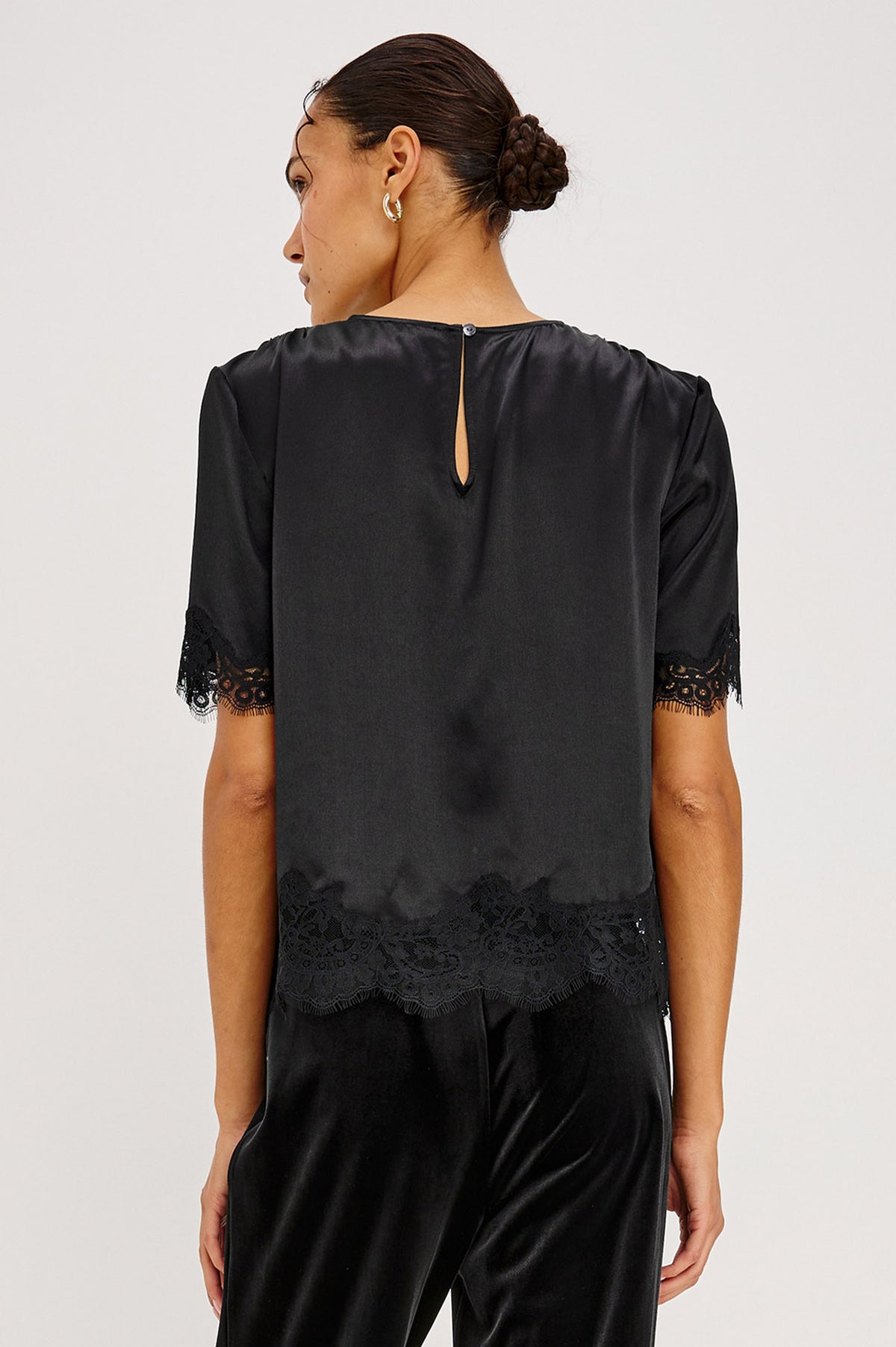 Sonora Shirt in Satin Crepe With Crew Neckline, Loose Boxy Fit, Shirred Shoulders, Short Sleeves, Button-Loop Back Keyhole, and Lace Trim in Black Colorway - Upper Body Back View Featured on Model