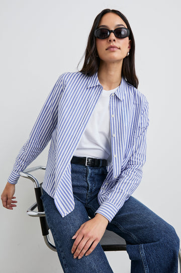 Stina Long-Sleeve Button Up with a Chest Patch Pocket in Mariner White Stripe Colorway, White and Blue Vertical Stripes - Front Unbuttoned Full Body View Featured on Seated Model