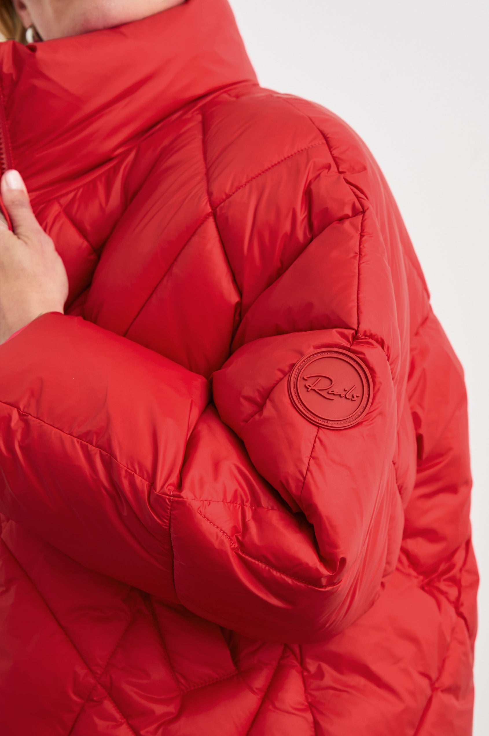Summit Cropped Puffer Jacket with a Mid-Neck Collar, Two Pockets and a Rails Logo on the Arm in Scarlet Colorway - Side View Featured on Model