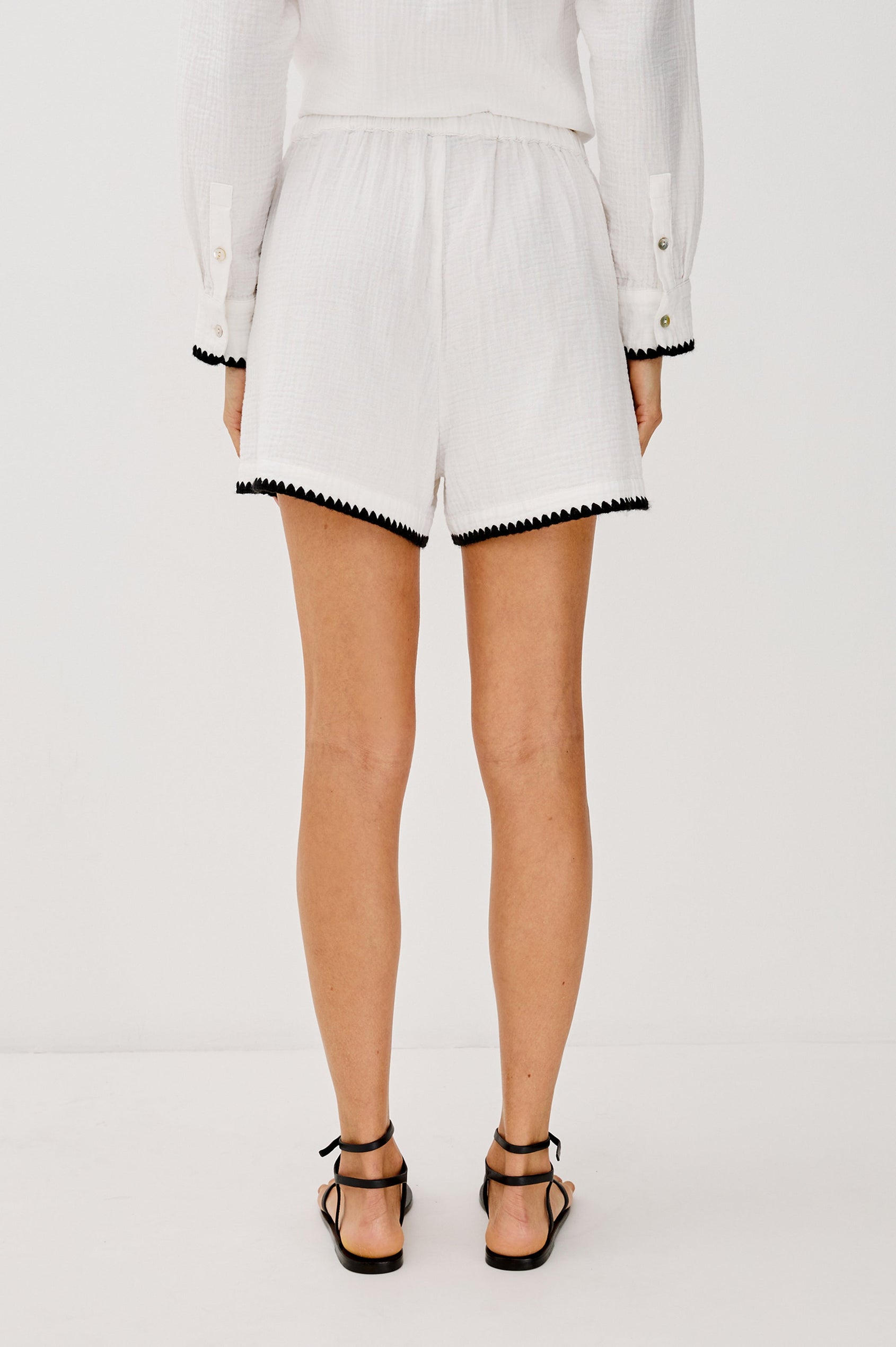 Sunny High Rise 3" Inseam Short with an Adjustable Waist Tie, Front Slash Pockets, White Body in Black Blanket Stitch Colorway. Back View Shown on Model. 