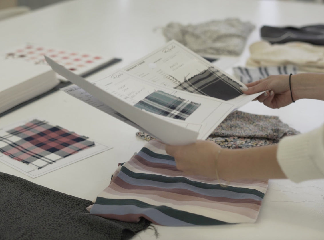 WHITE TABLE WITH MULTIPLE FABRIC SAMPLES (SMALL SQUARES OF FABRIC IN VARIOUS COLORS) ON TOP OF THE TABLE