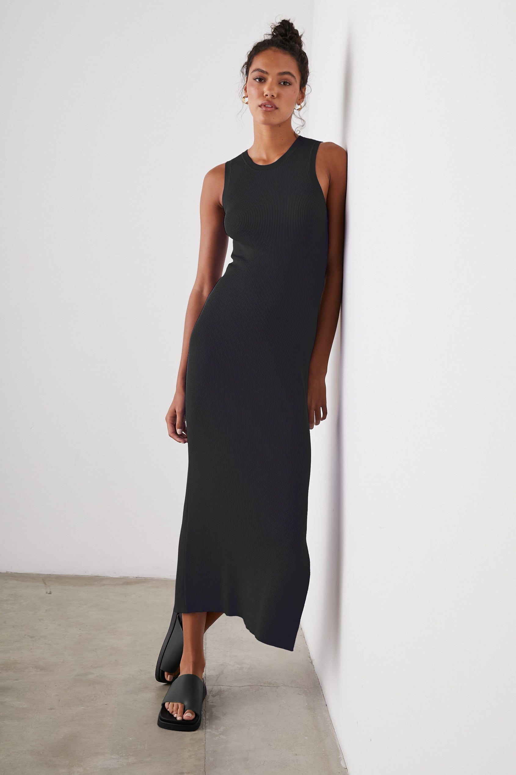 Syd Ribbed, Sleeveless Midi Dress with Wide Shoulder Straps, a Side Slit, and a Cutout that Spans the Lower Back in Black Colorway - Front Full Body View Featured on Model  
