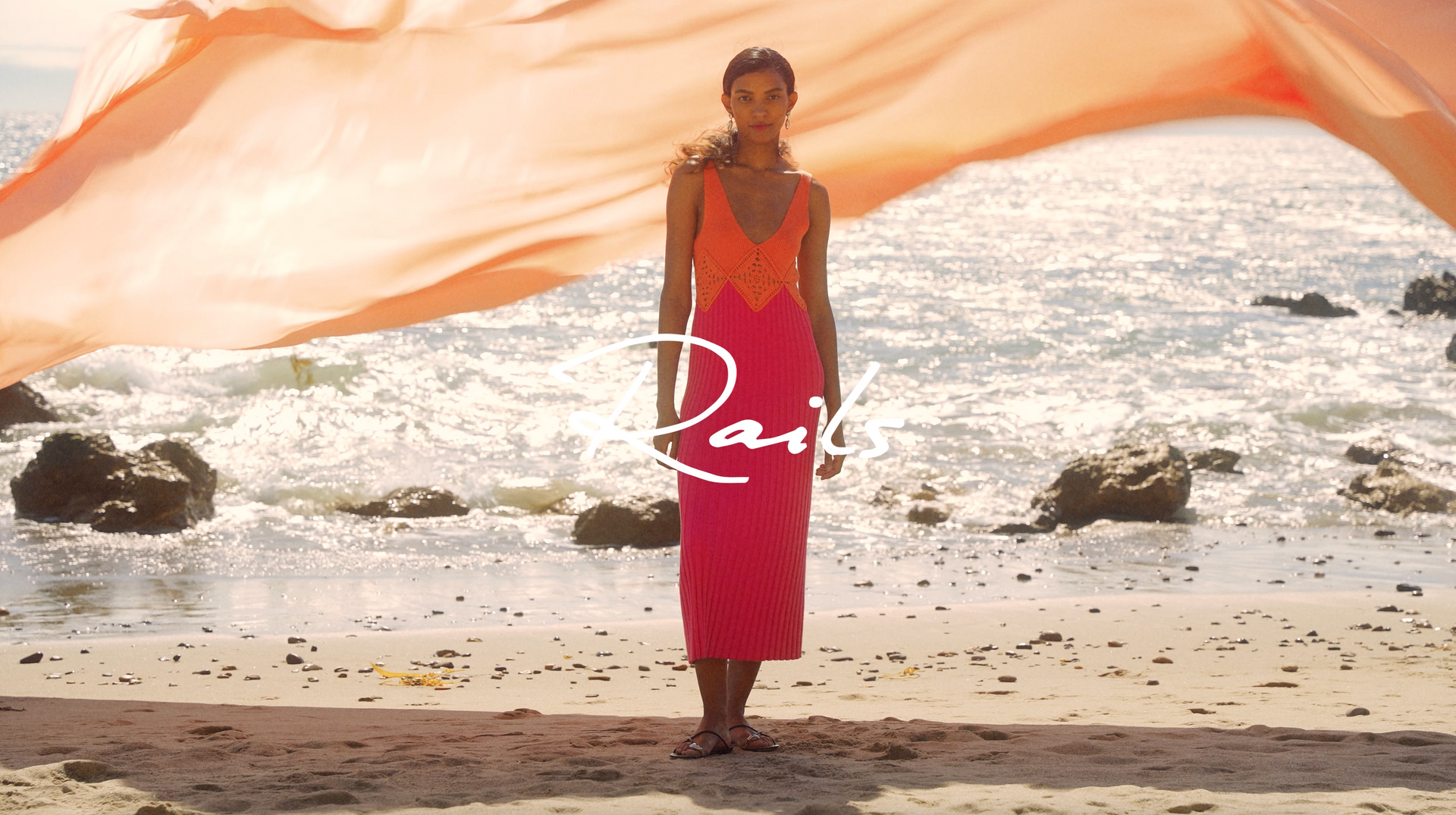FRONT FULL BODY EDITORIAL IMAGE OF MODEL ON THE BEACH WEARING THE TARYN DRESS IN PAPAYA COLORBLOCK