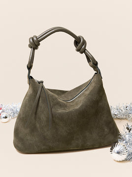 An olive green suede hobo handbag with a knotted leather top handle, displayed on a light beige background with silver tinsel accents.
