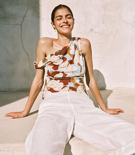 Woman in a floral one shoulder top and white pants