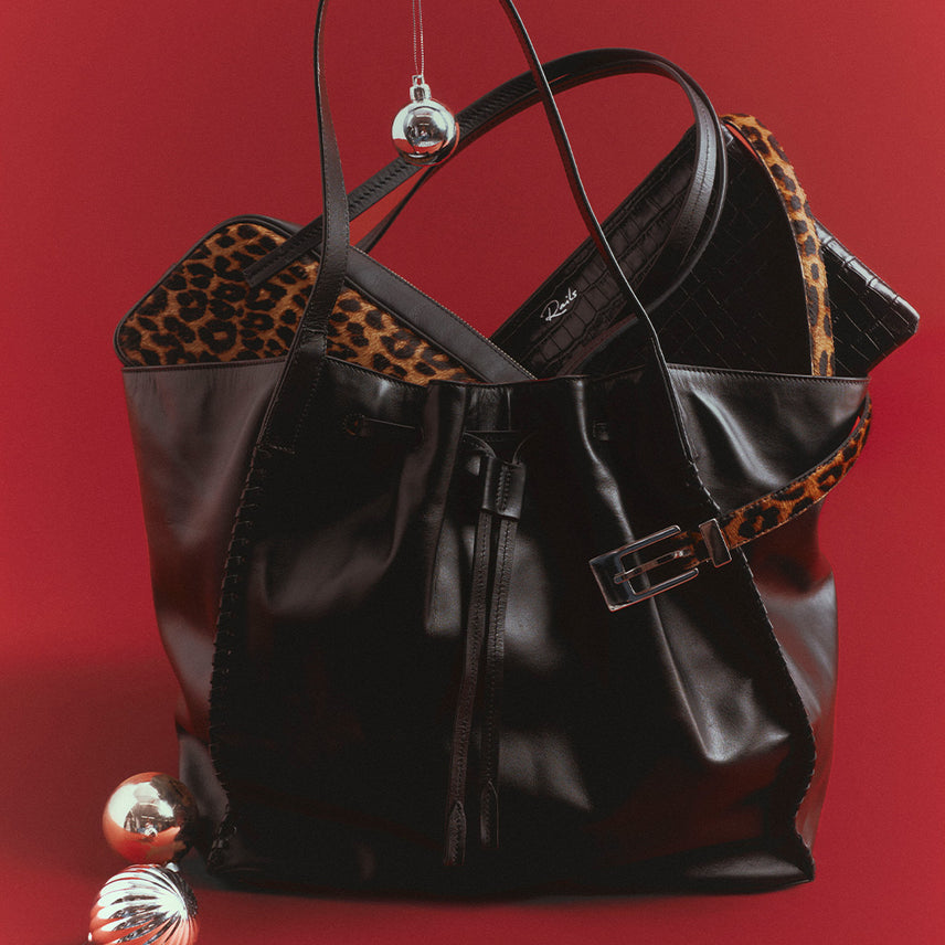 Variety of different colored and style handbags placed against a red background.