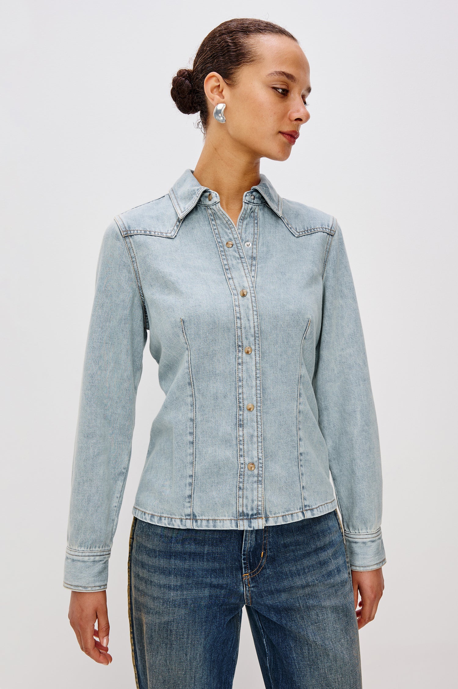 Taiana Cotton Lyocell Denim Shirt in Light Blue Wash With Western Yoke, Front and Back Darts for Fitted Silhouette, Front Pearl Snap Buttons, and Long Sleeves in Bleached Indigo Colorway - Upper Body Front View Featured on Model