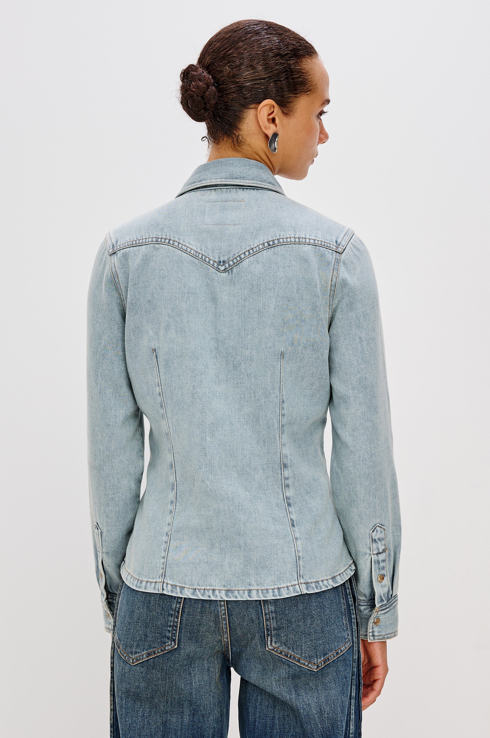 Taiana Cotton Lyocell Denim Shirt in Light Blue Wash With Western Yoke, Front and Back Darts for Fitted Silhouette, Front Pearl Snap Buttons, and Long Sleeves in Bleached Indigo Colorway - Upper Body Back View Featured on Model