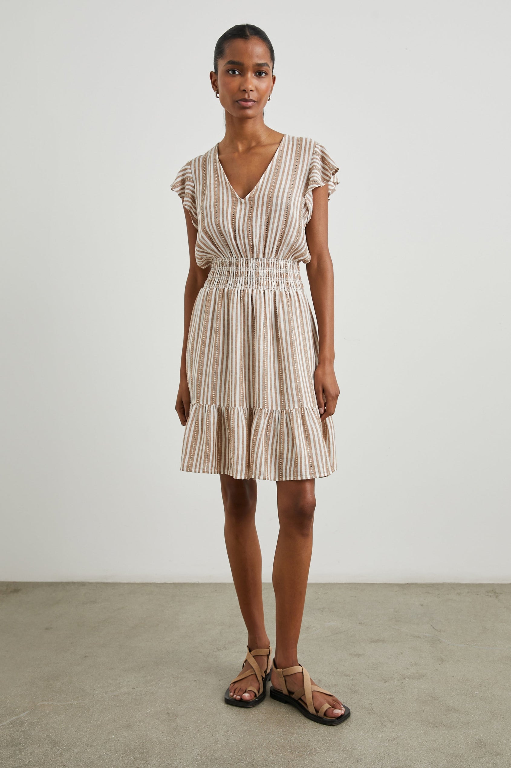 Tara Short Sleeve, Above the Knee Dress with a Smocked Waist, V Neck, Flutter Cap Sleeves, and Tiered Skirt with a Ruffled Hem in Palo Santo Stripe Colorway, with Textured Brown Vertical Stripes on White - Front Full Body View Featured on Model 