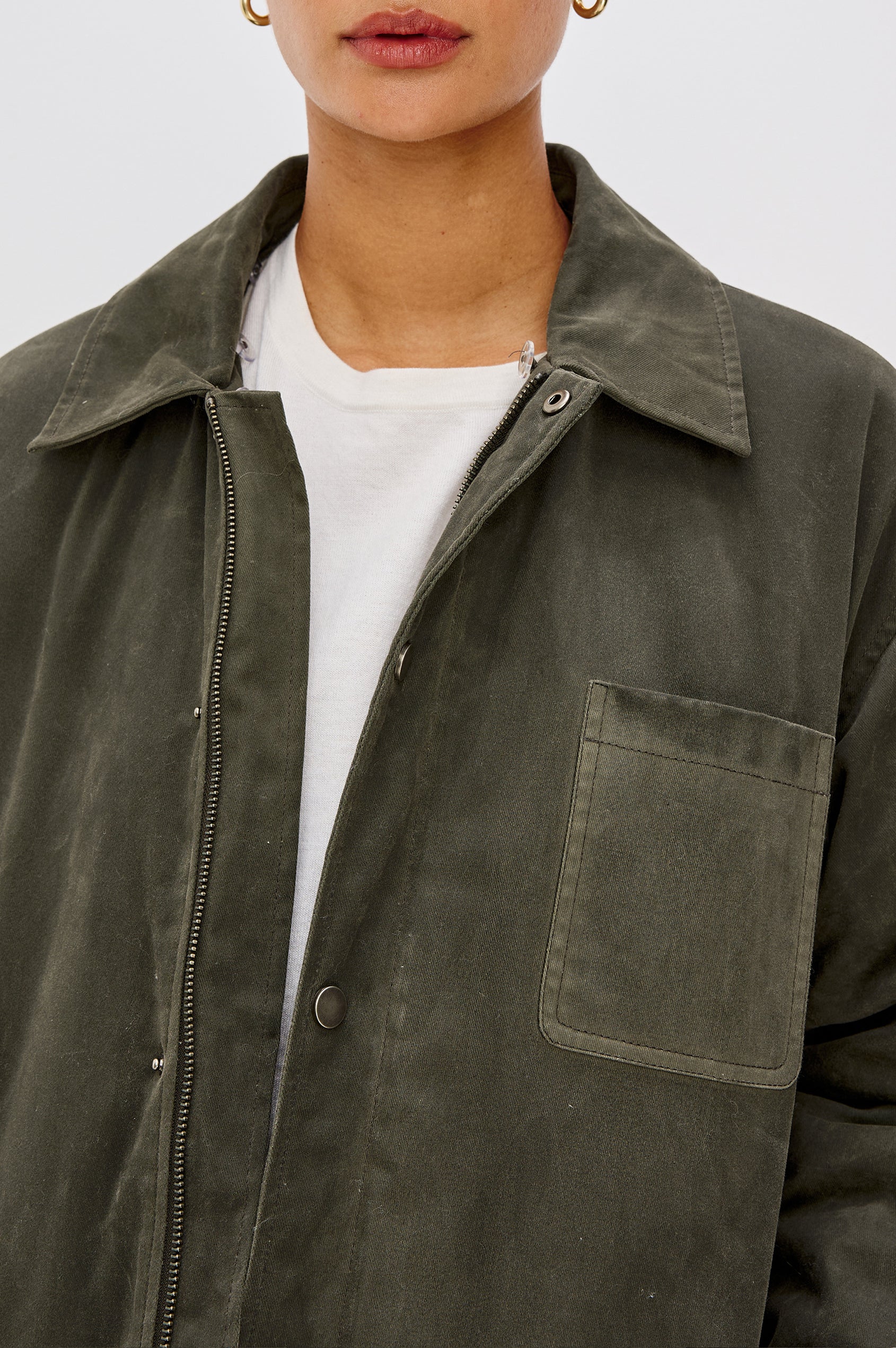 An umber waxed cotton canvas jacket with a removable vegan-fur collar. The jacket has a zip front with snap closures, quilted lining, chest patch pocket, and side pockets for a functional, workwear-inspired look. Close Up View Featured on Model.