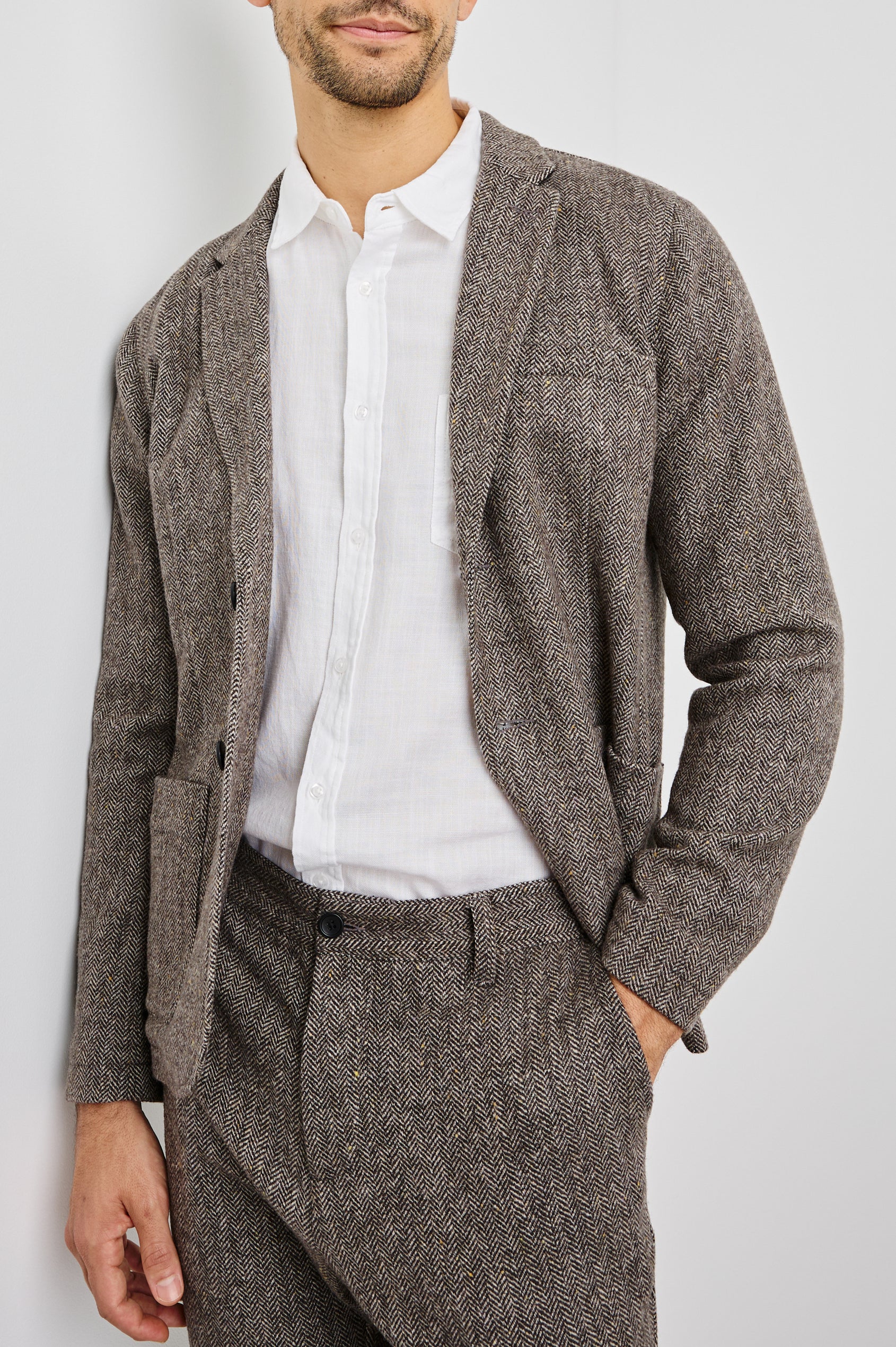 Reynard Blazer with Two Button Closure, Two Front Pockets, a Chest Welt Pocket, Herringbone Fabric in Highland Tweed Colorway, a Brown - Front View Featured on Model