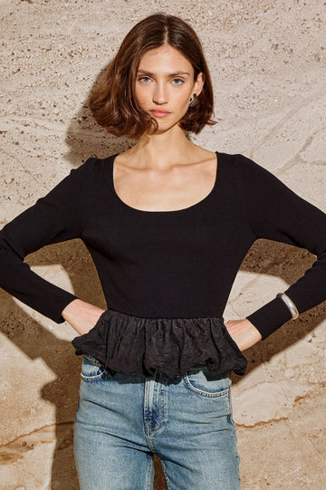 The Tillie is a fitted, long-sleeved sweater top with a contrasting cotton poplin ruffle at the hem in Black Colorway - Stylized Front View Featured on Model.
