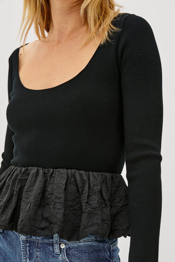 The Tillie is a fitted, long-sleeved sweater top with a contrasting cotton poplin ruffle at the hem in Black Colorway - Close up of Details on model