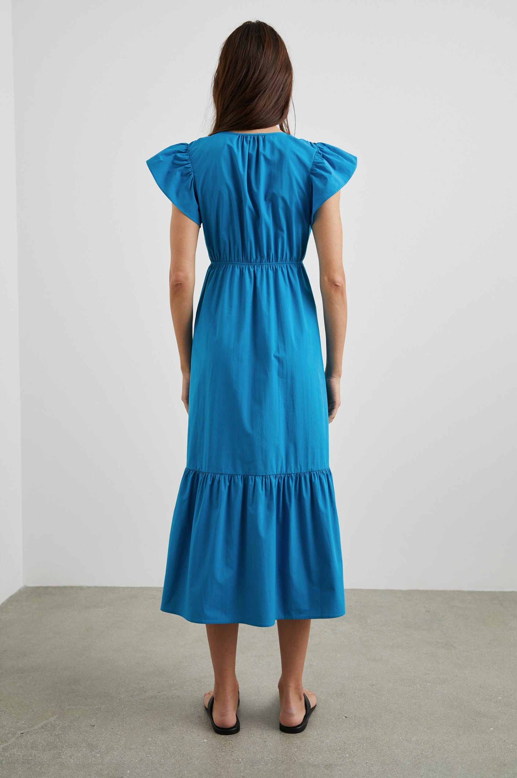 Tina Short Sleeve Midi Dress with Flutter Sleeves, a Deep V Neck with a Cutout and a Tiered Skirt in Turkish Tile Colorway, a Blue - Back Full Body View Featured on Model 