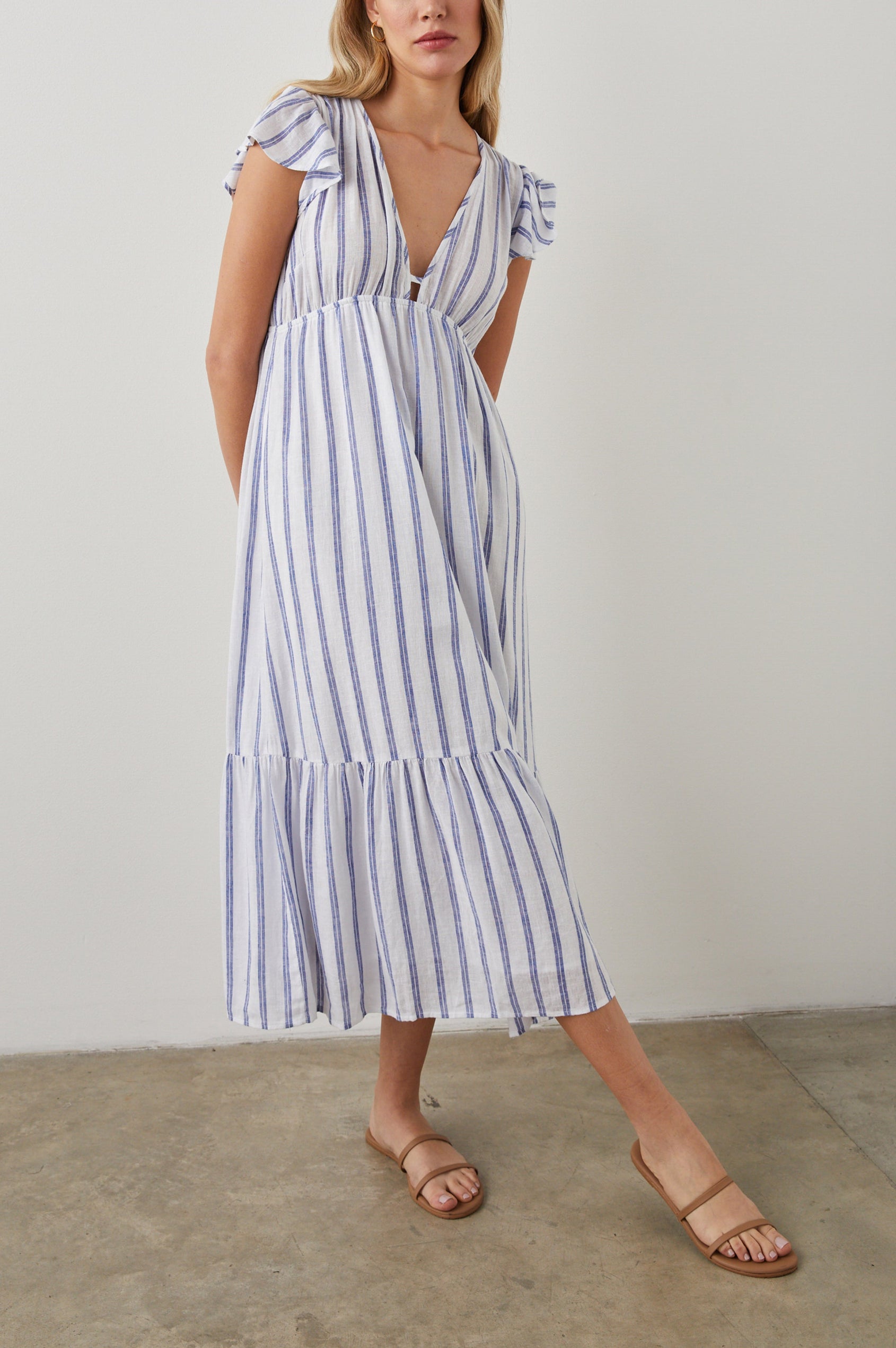 Tina Short Sleeve Midi Dress with Flutter Sleeves, a Deep V Neck with a Cutout and a Tiered Skirt in Villa Stripe Colorway, with Thin Vertical Blue Stripes on White - Front Full Body View Featured on Model 